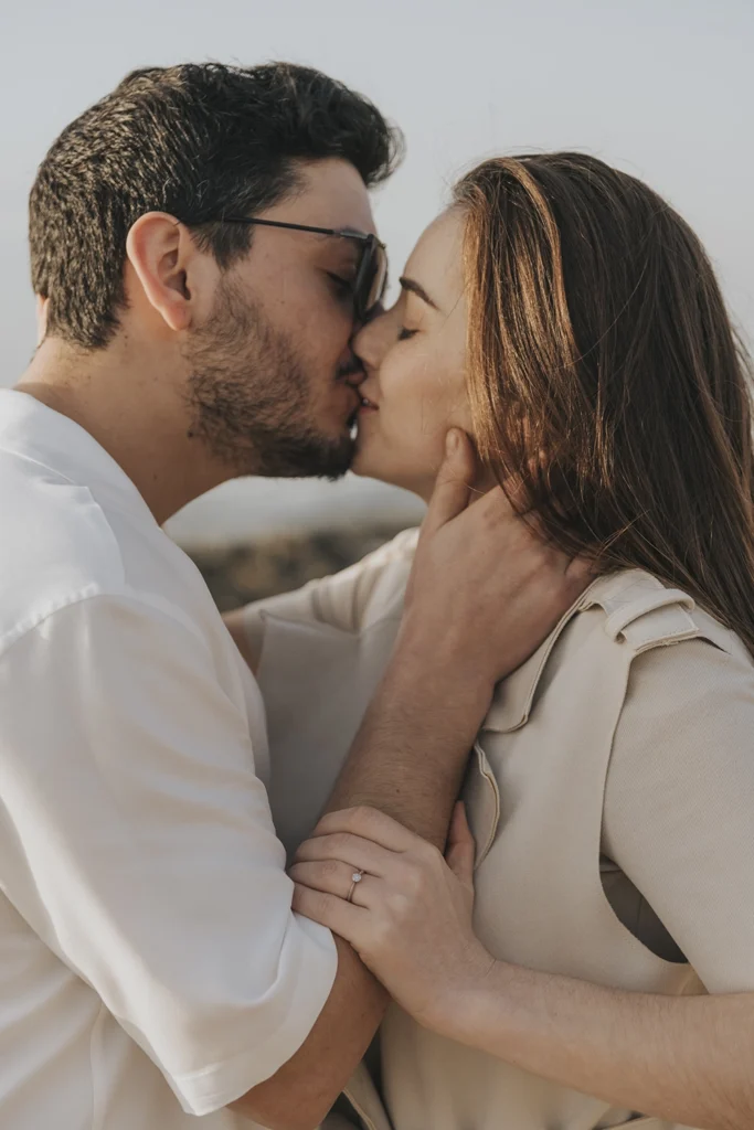 Casal beija-se sorrindo, expressando felicidade e amor genuíno.