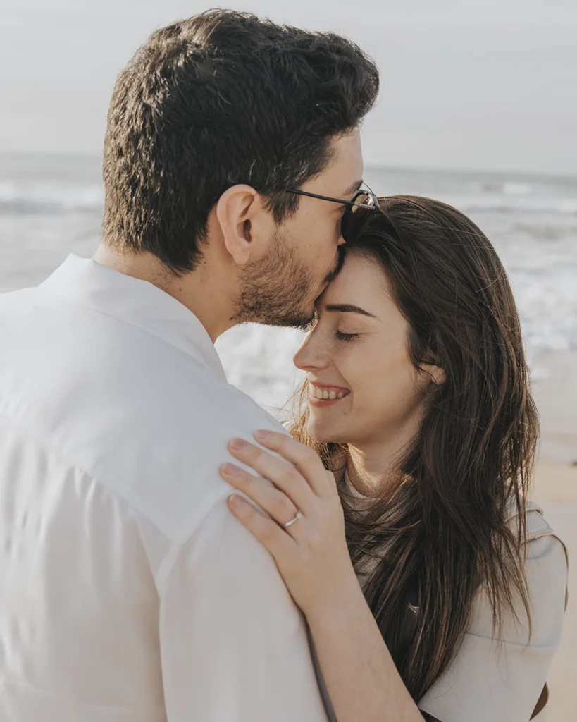 Casal em momento terno, com um beijo na testa transmitindo carinho e cumplicidade.