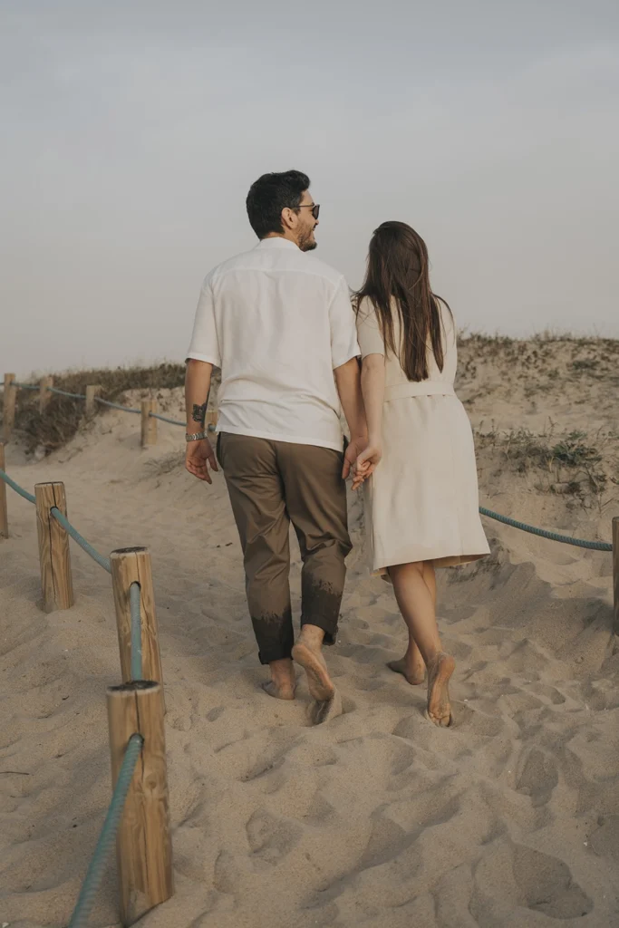 Casal caminha pelas dunas, imerso na paisagem natural e no momento a dois.