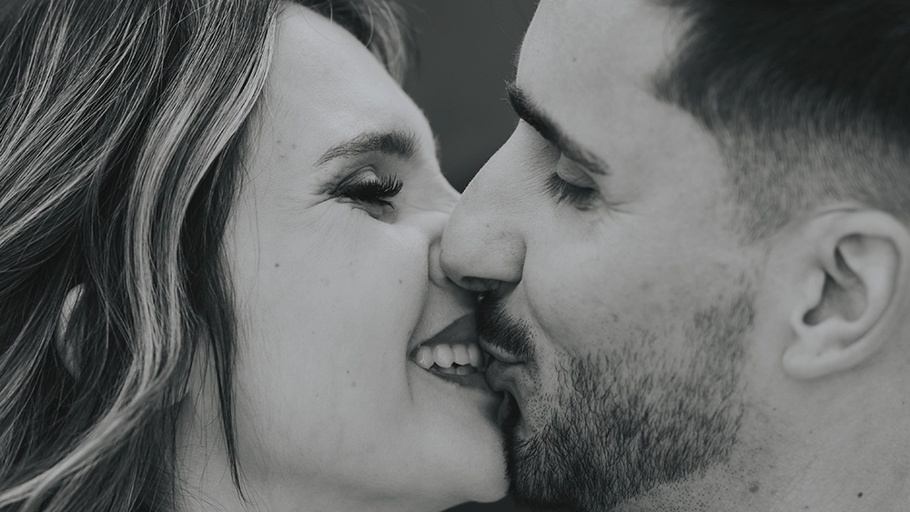 Detalhe de um beijo feliz entre os noivos, capturado de forma intimista e cheia de carinho.